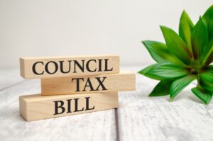 Council tax bill written on wooden block next to a plant